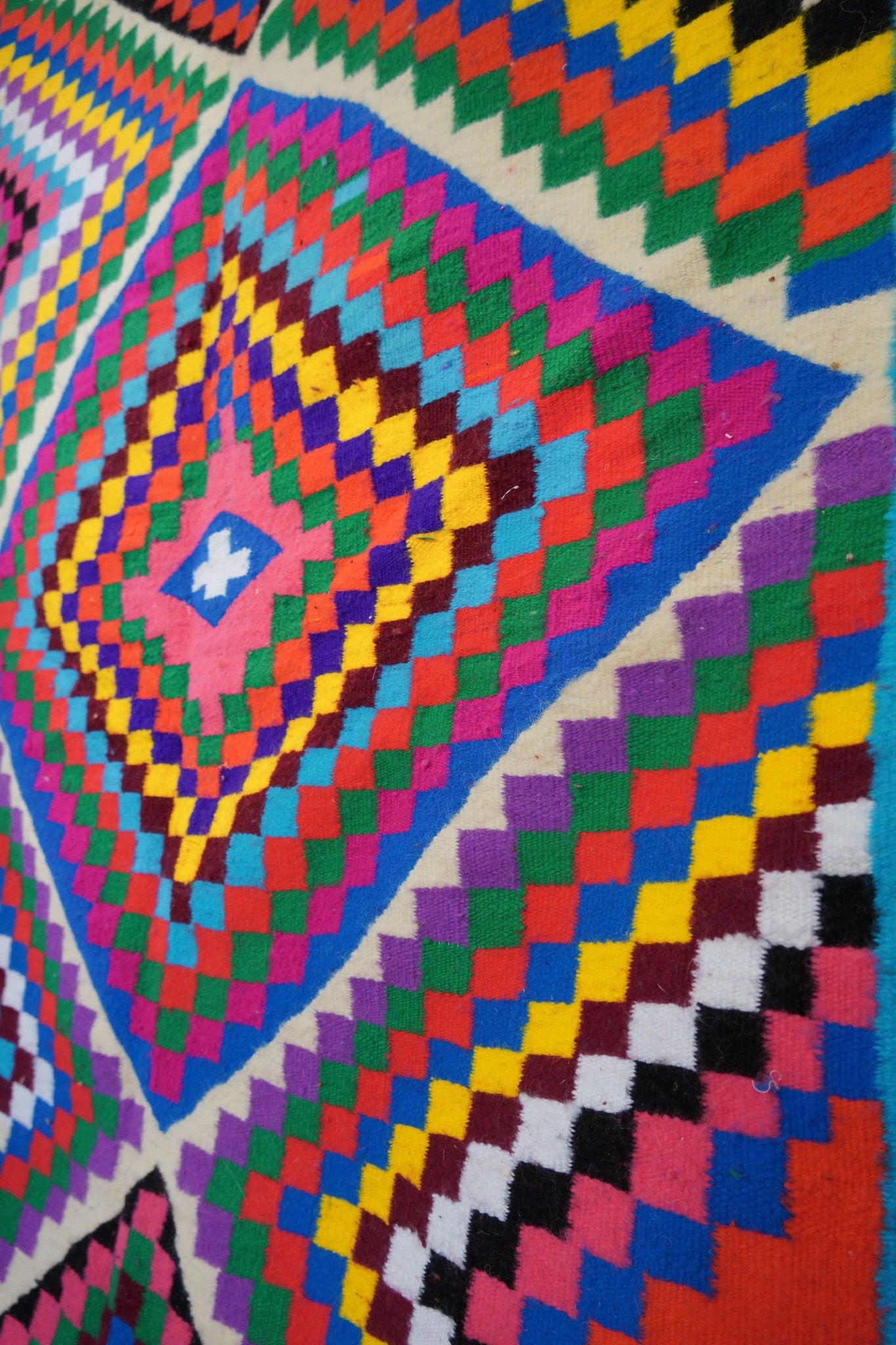 Detailed view of the central diamond on multicolor wool rug.