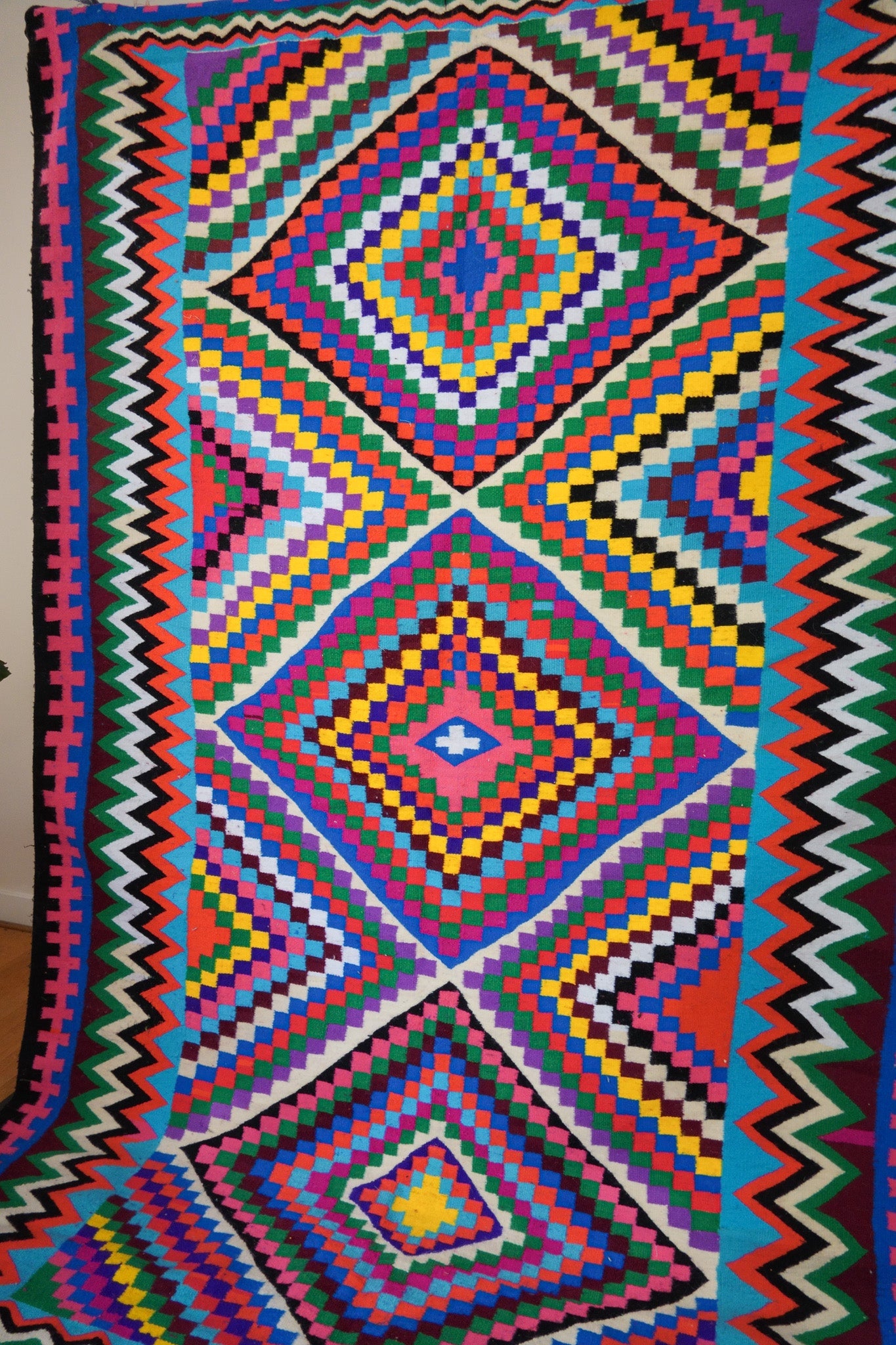 Close-up of multicolor checkered diamond weave on handmade wool rug.