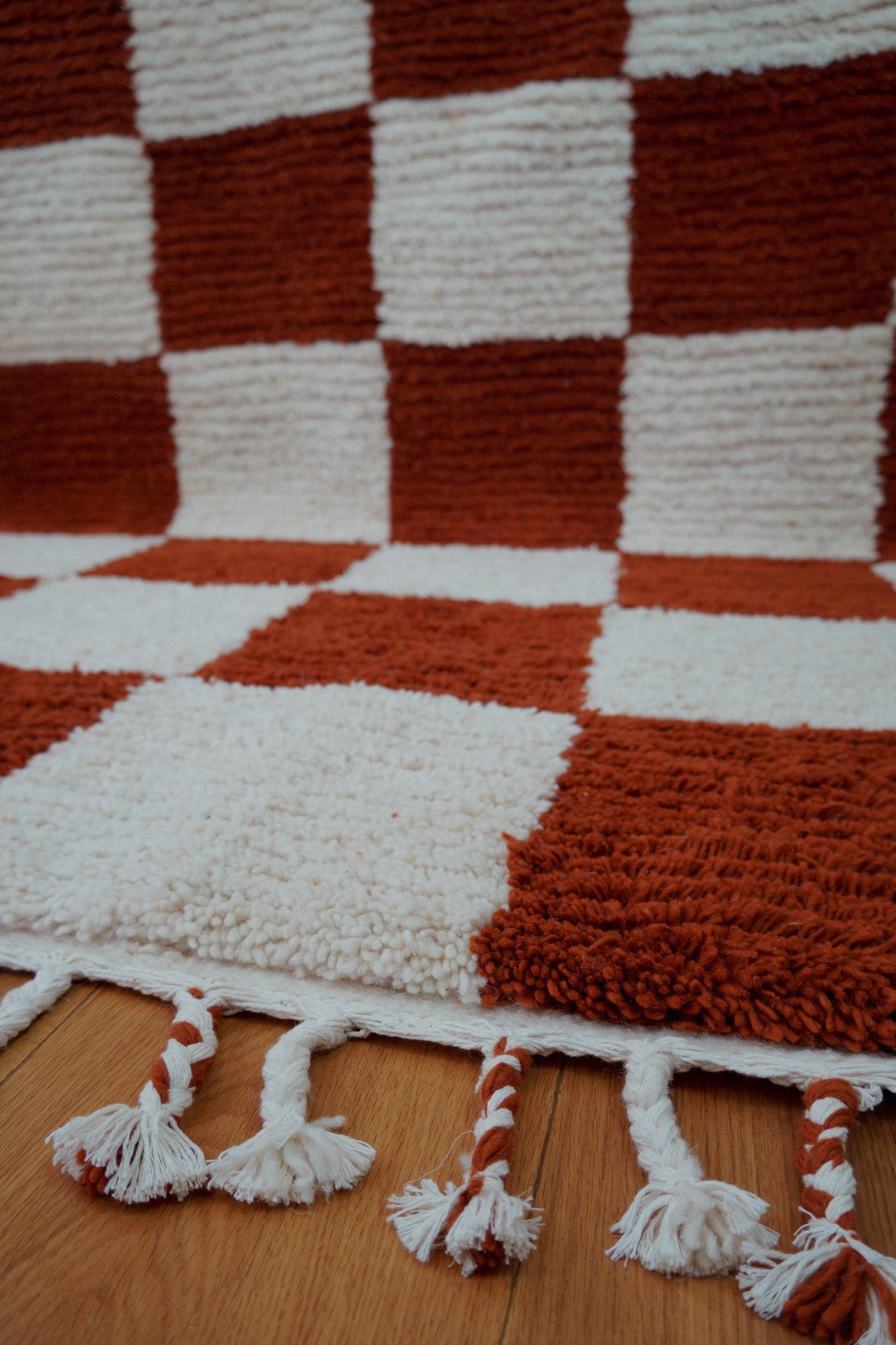 Low angle shot showing texture, checkered pattern, and the edge of the handmade wool rug