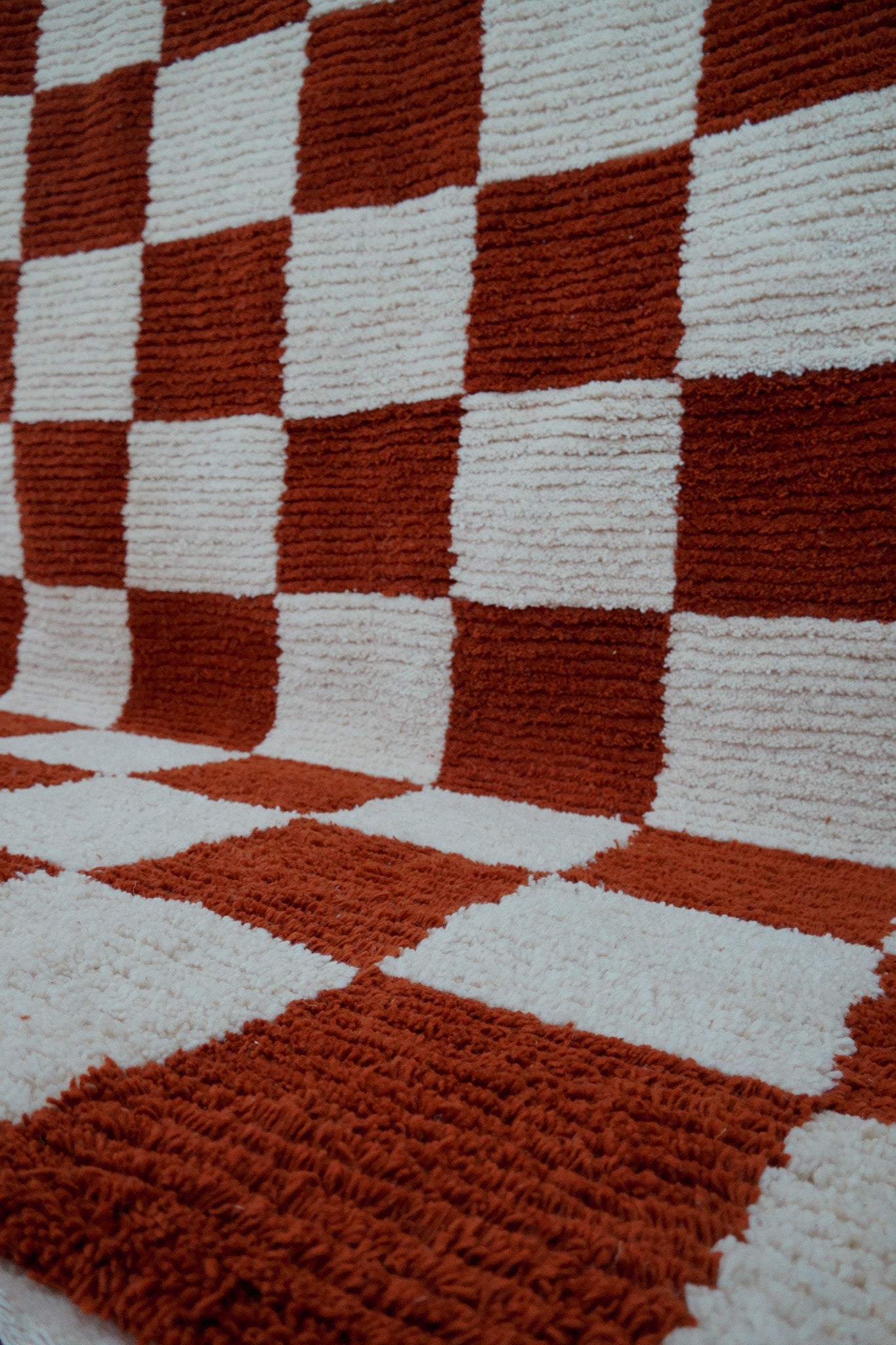 Close-up of diagonal angle of the Fatma handmade wool rug showing full checkered design in styled room