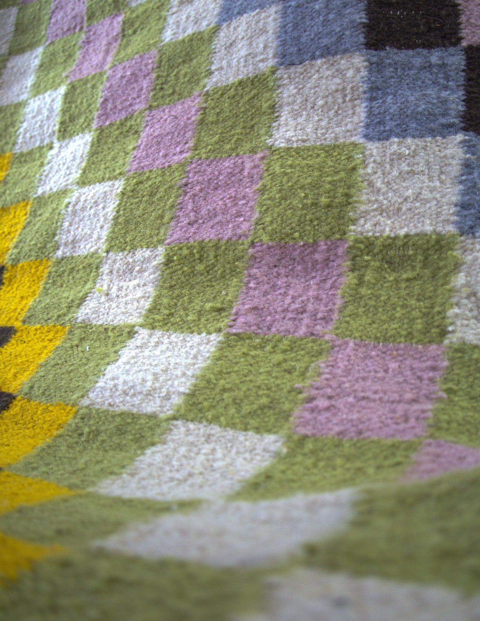Detailed view of the handwoven wool stitching and playful color blends of the Hiba checkered rug
