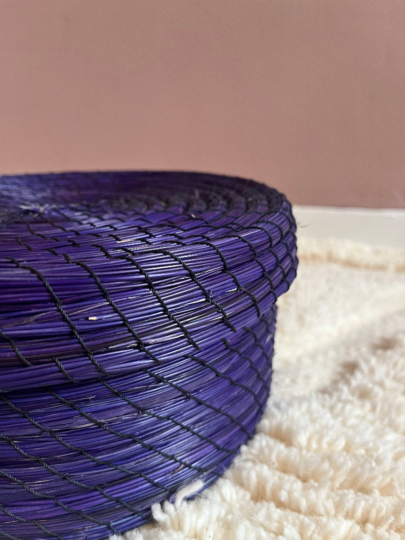 Angled close-up of deep purple handwoven straw basket.