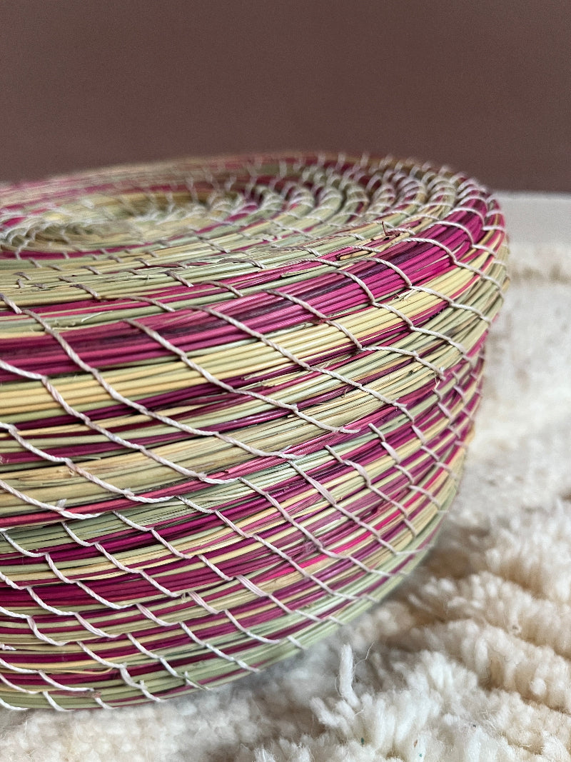Close-up detail of the natural green and pink straw weaving.