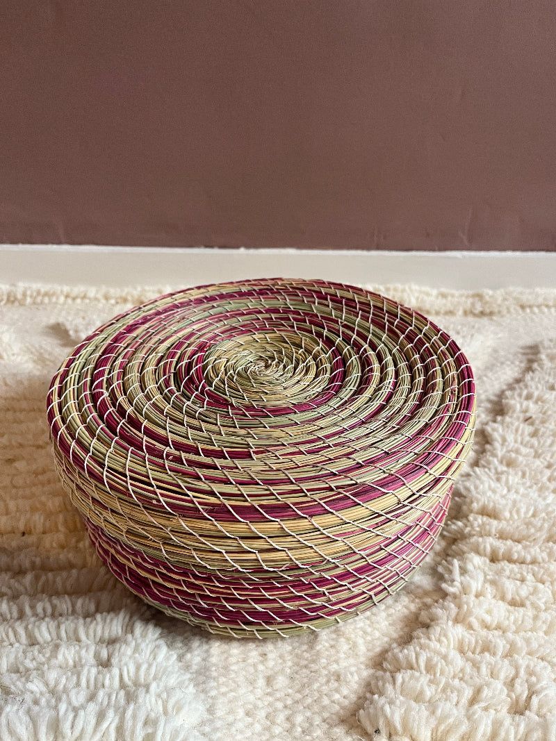 Overhead top view of Karima handmade straw basket with natural green and pink pattern.
