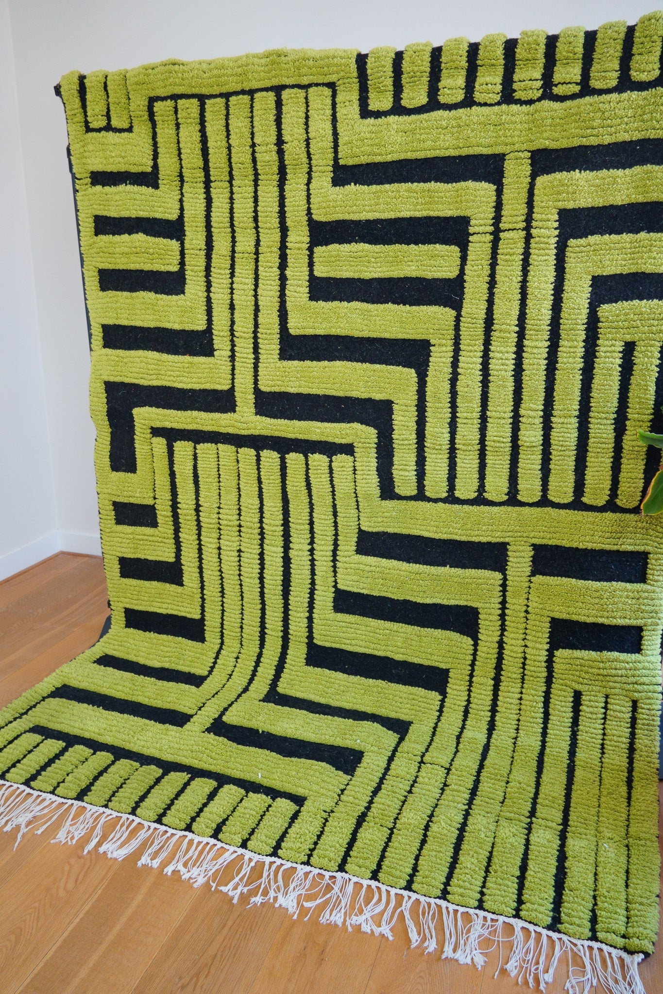 Angle close-up of geometric green and black wool pattern from the Kenza rug