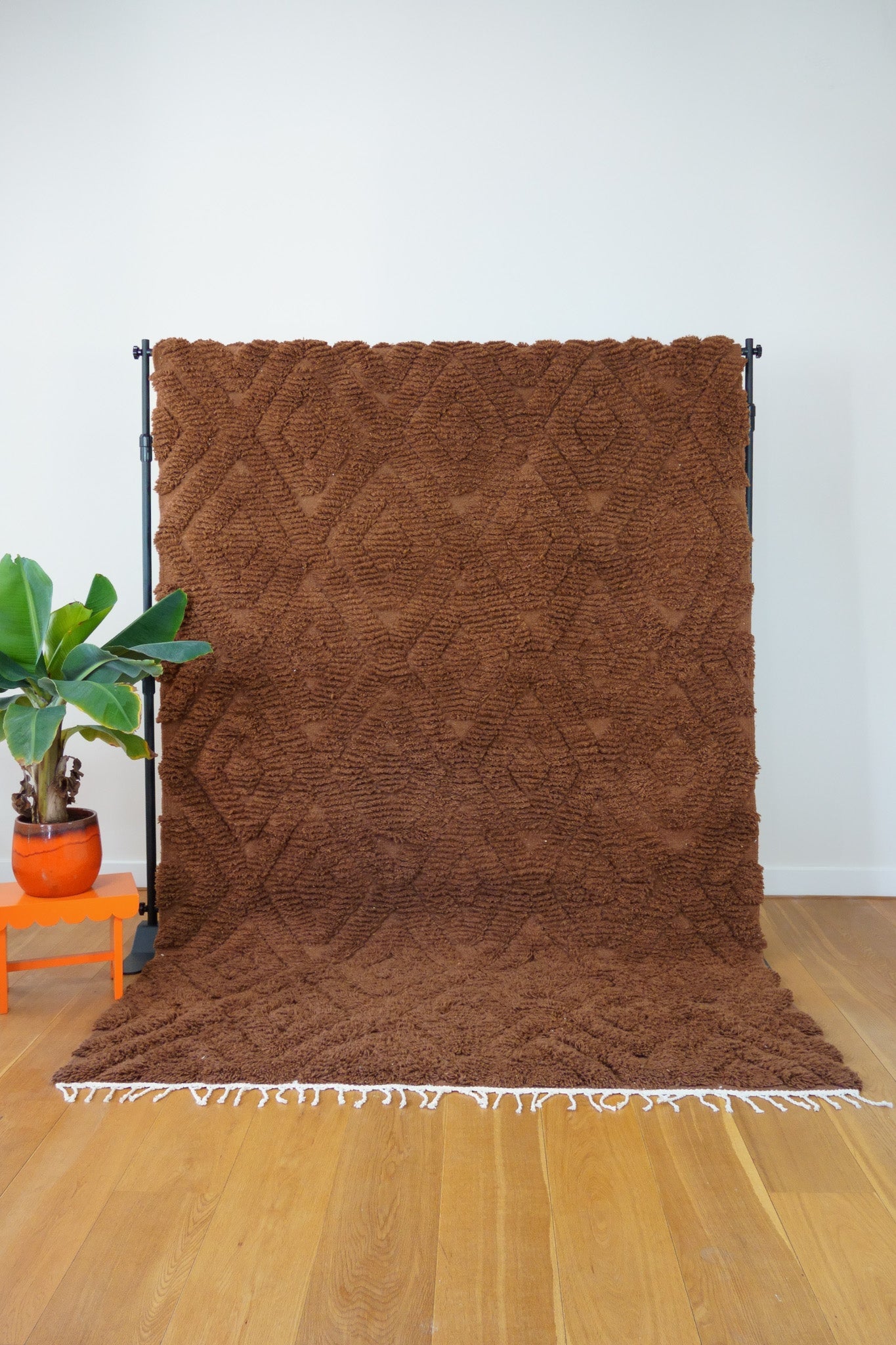 Full front view of the Leila handmade Berber rug in deep brown with raised diamond pattern, upright on wooden floor