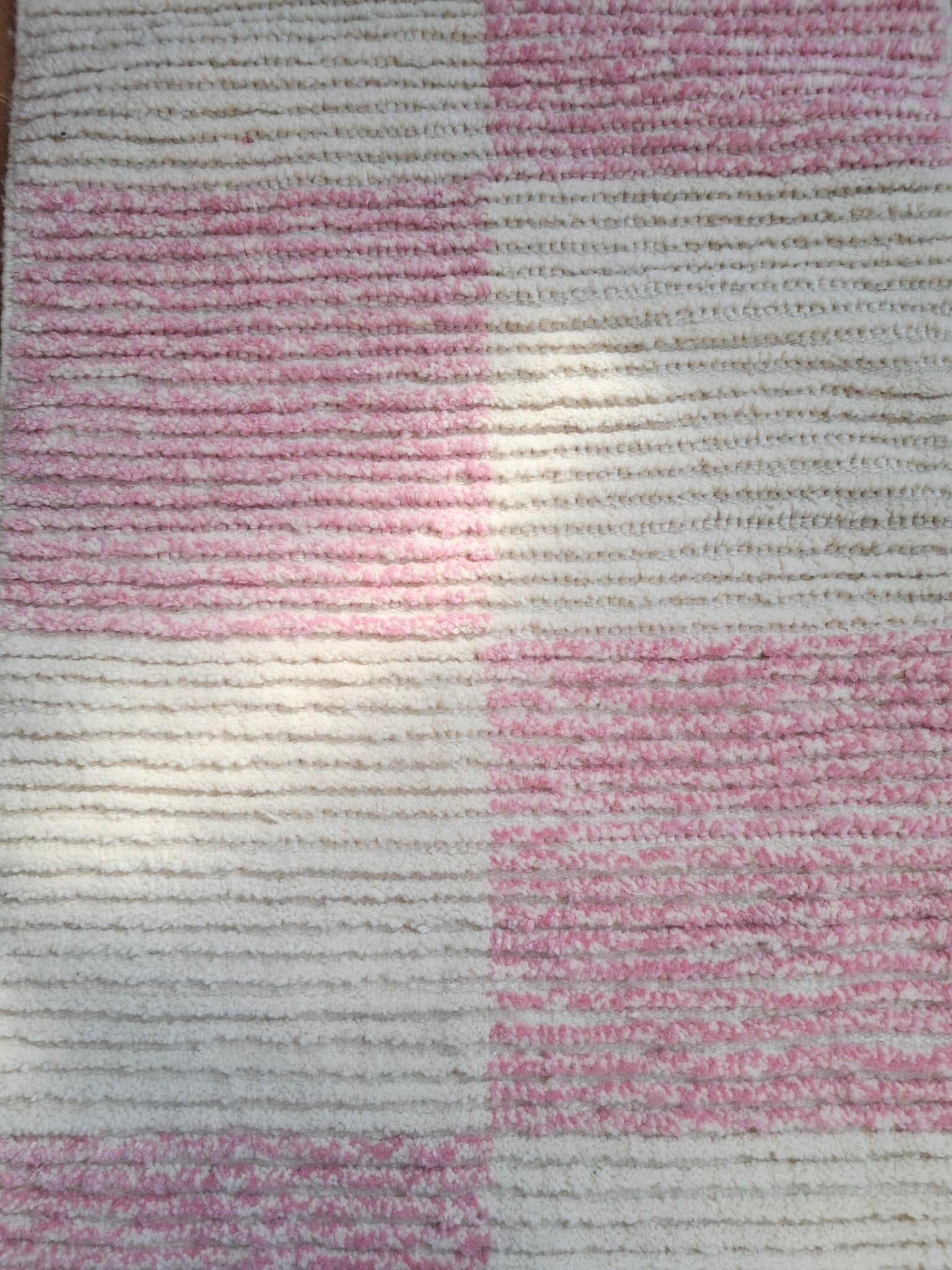 Close-up of Lina rug’s texture showing soft pink and off-white wool pattern in a raised checkered weave