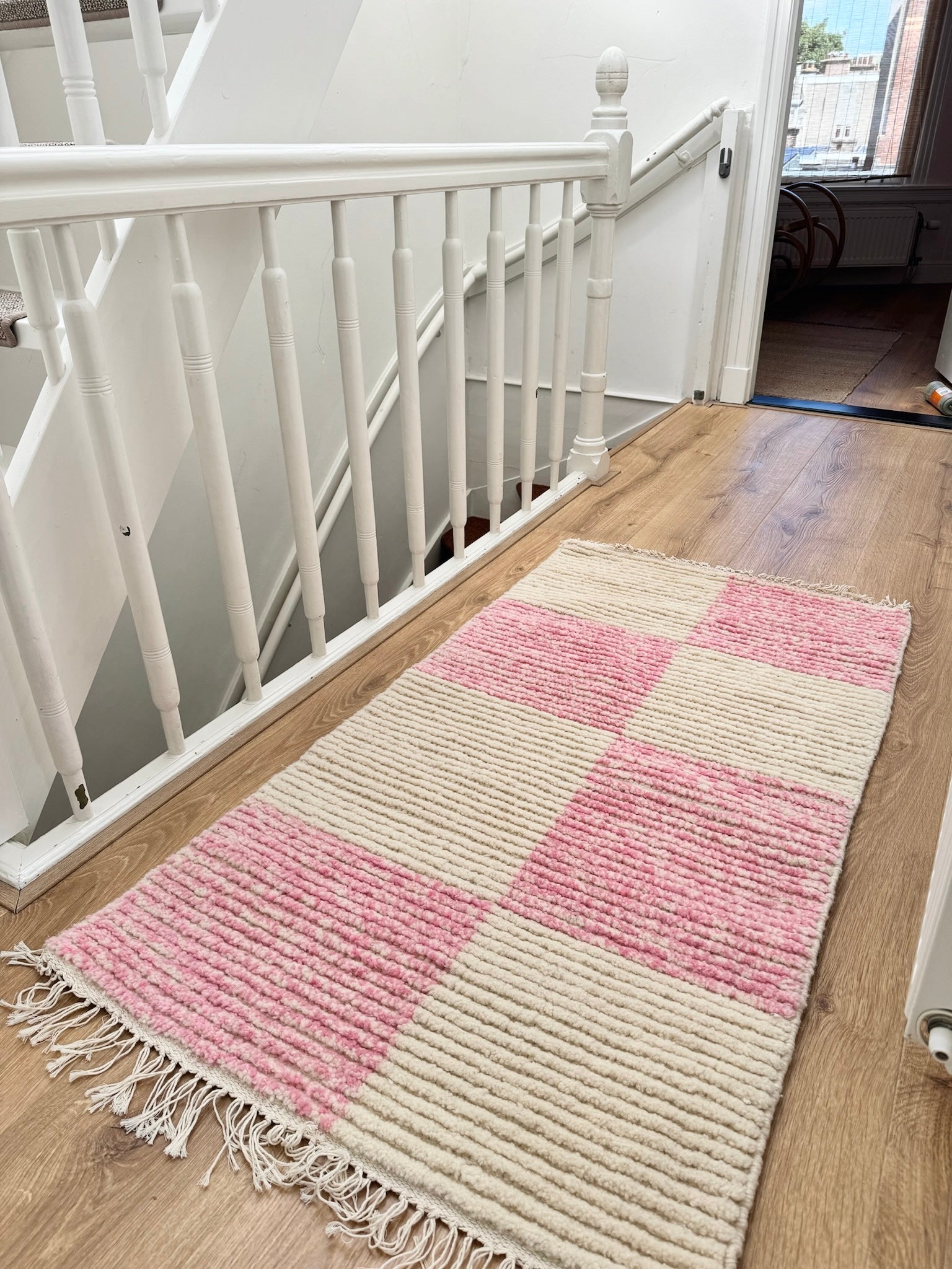 Lina rug placed in a bright hallway, displaying its soft checkered tones and rectangular shape in a real-life home setting