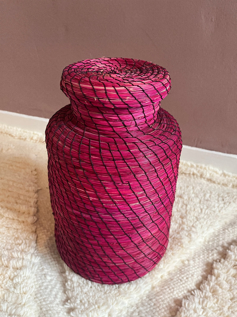 Angled view of handmade straw basket Nabila in vibrant pink.