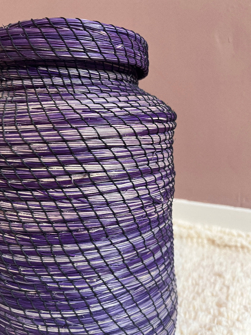 Close-up detail of handwoven straw texture in deep purple basket.