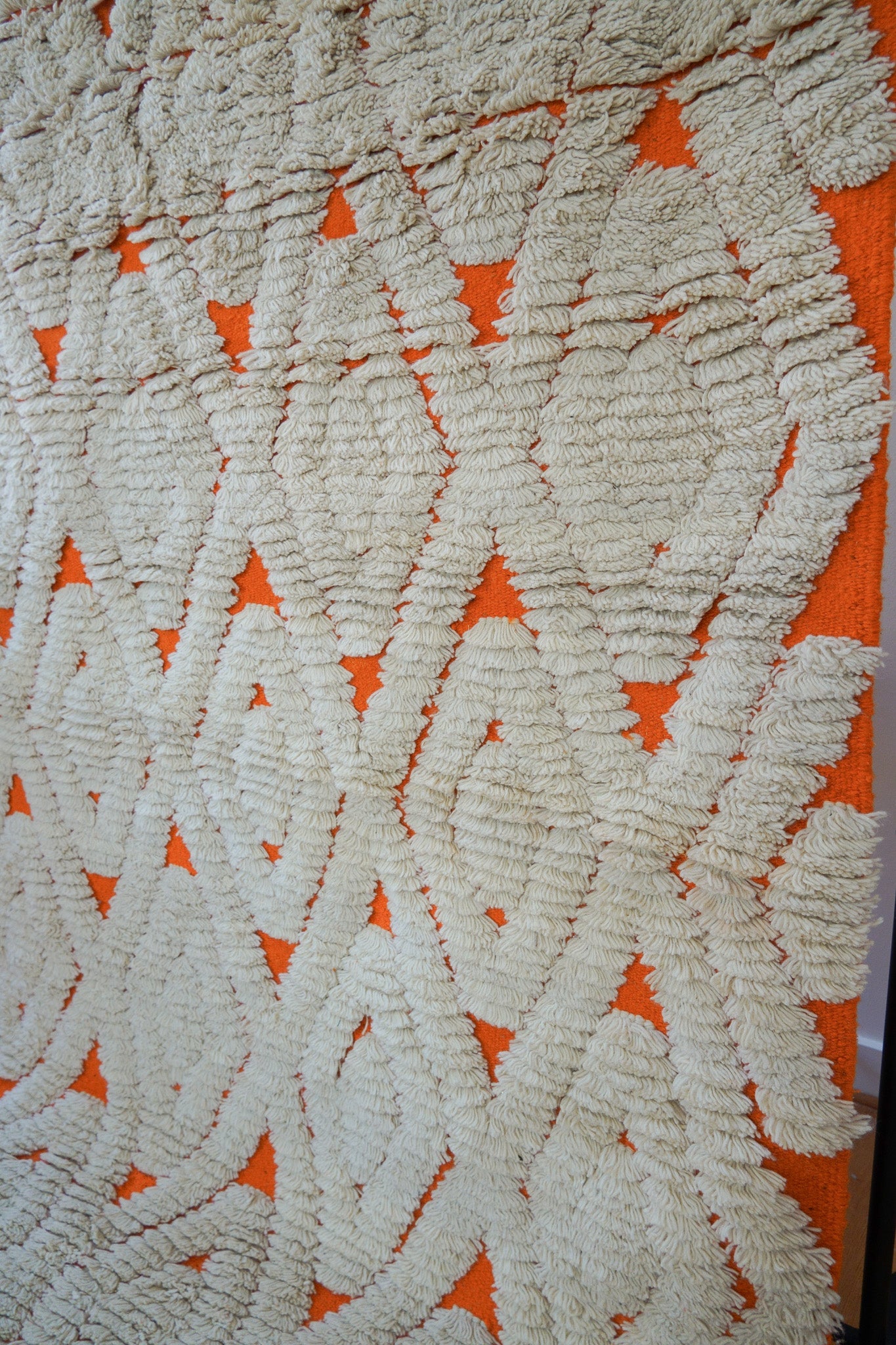 Detailed texture of shaggy wool pile with orange base and cream diamonds