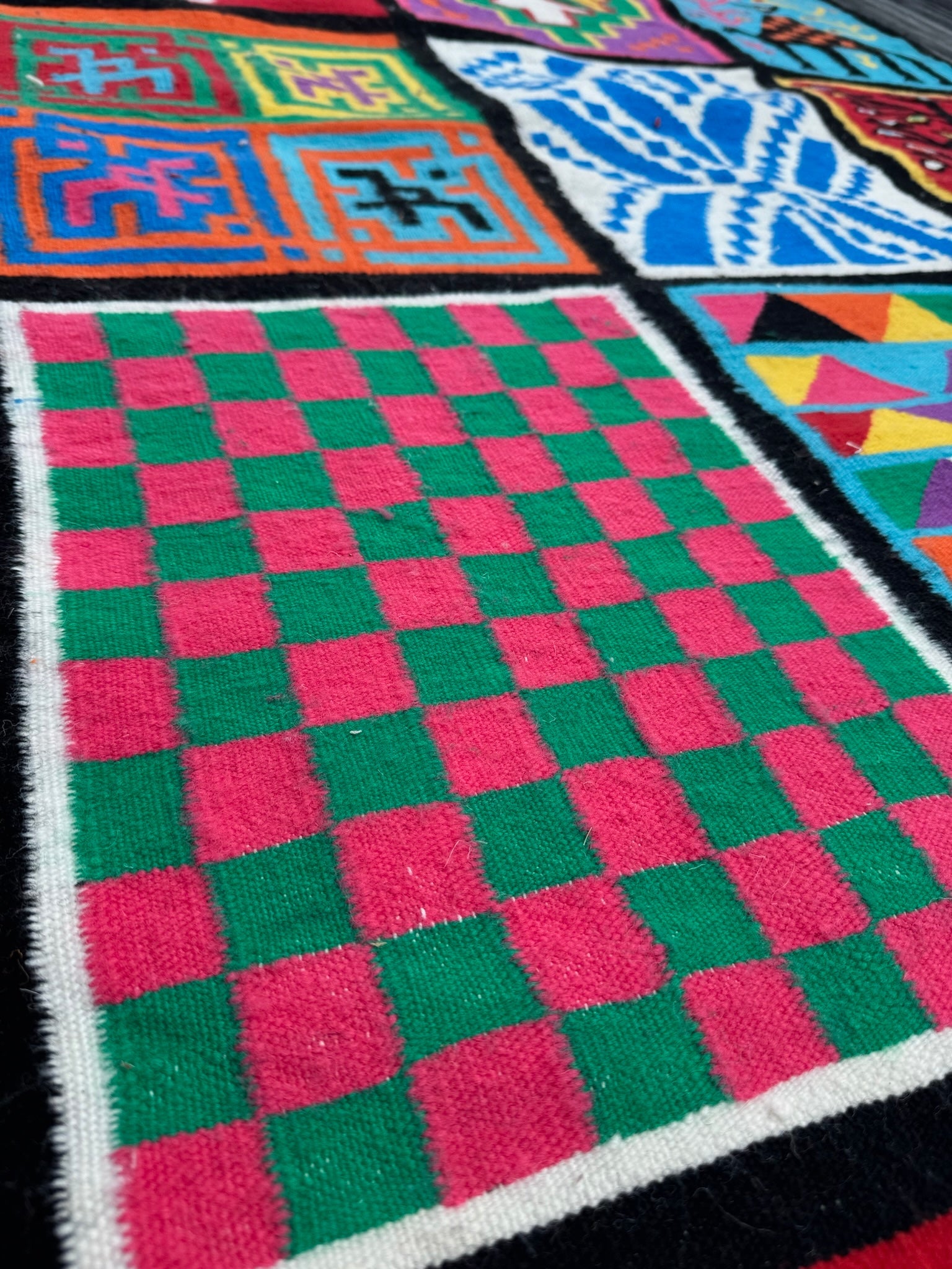 Detail of green and red checkerboard section in Zina wool rug.