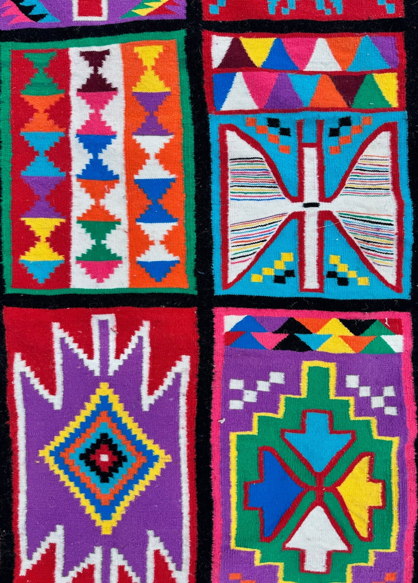 Detailed view of small geometric motifs on multicolor wool rug.
