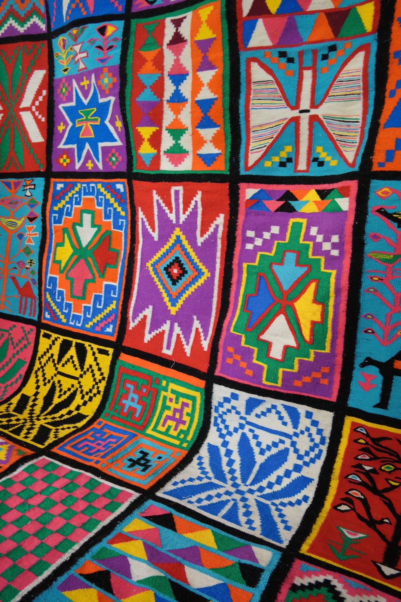 Detail view of colorful geometric designs in handmade wool rug.