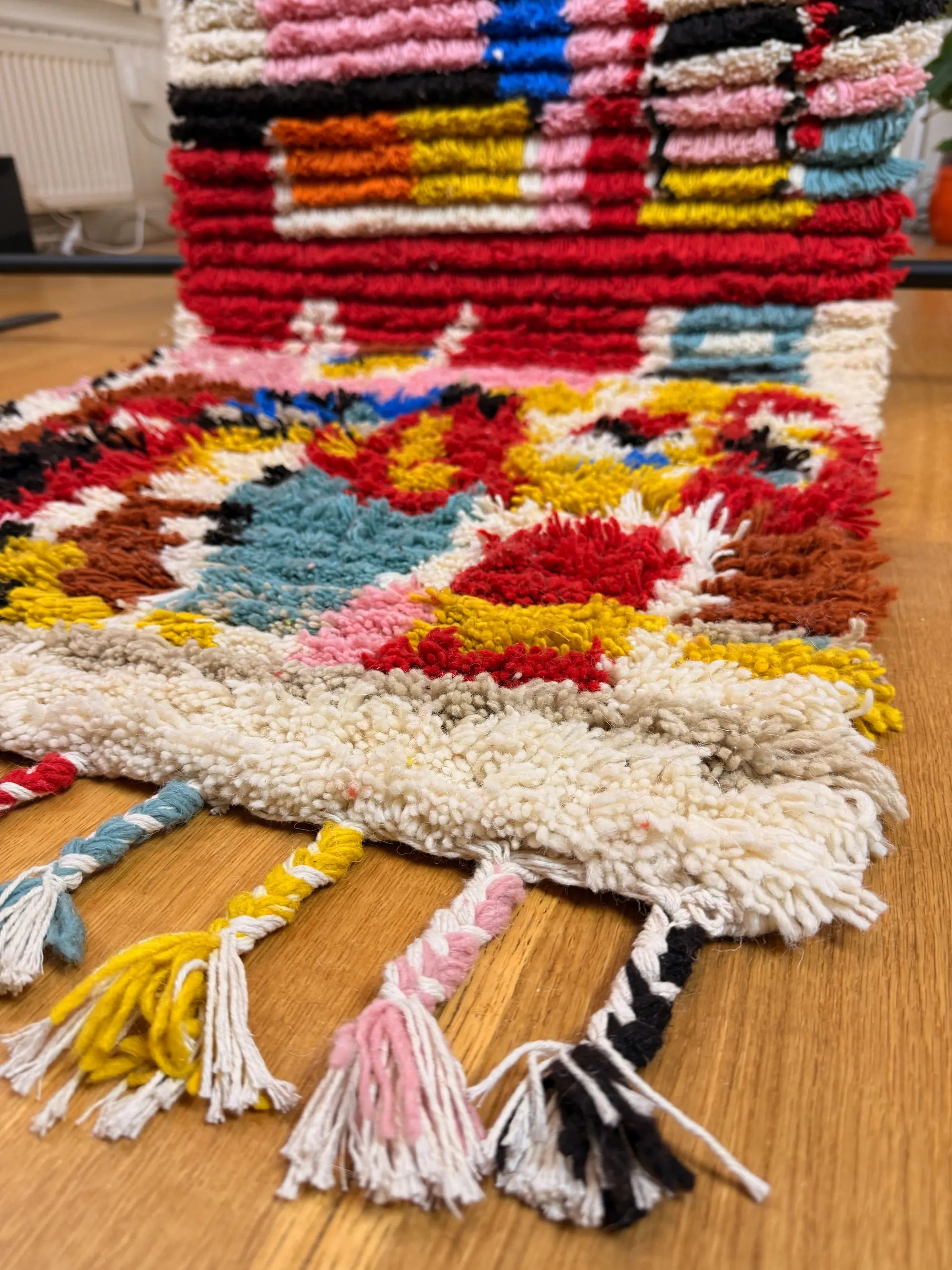 Close-up of the multicolour hand-knotted fringe on the Hafsa handmade shaggy Berber wool runner, twisted in yellow, pink, teal and black, Tunisia.