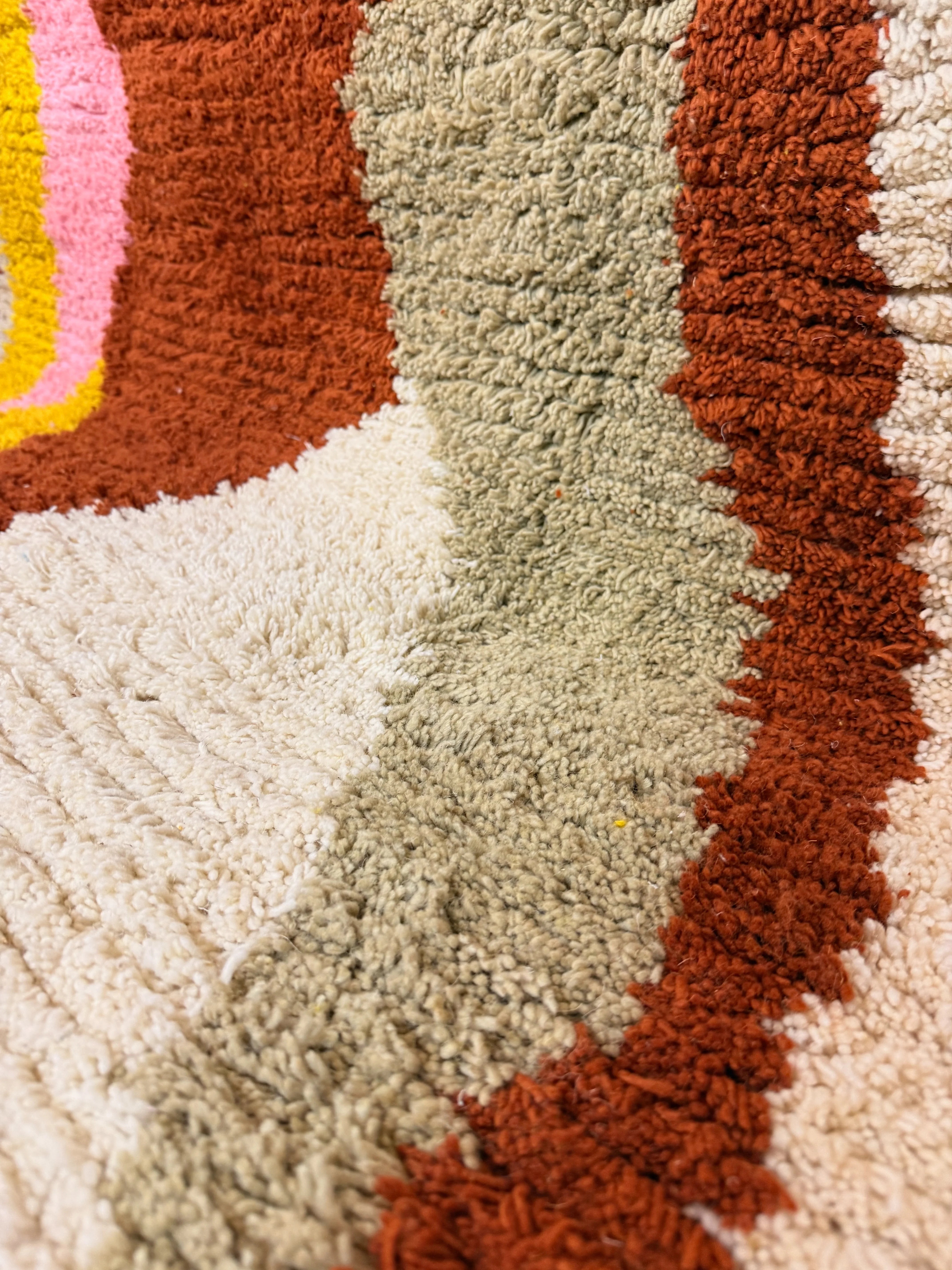 Close-up of the dense wool pile on the Jamila Berber rug, showing the hand-knotted texture and colour transitions between grey, cream and burnt orange, Tunisia.