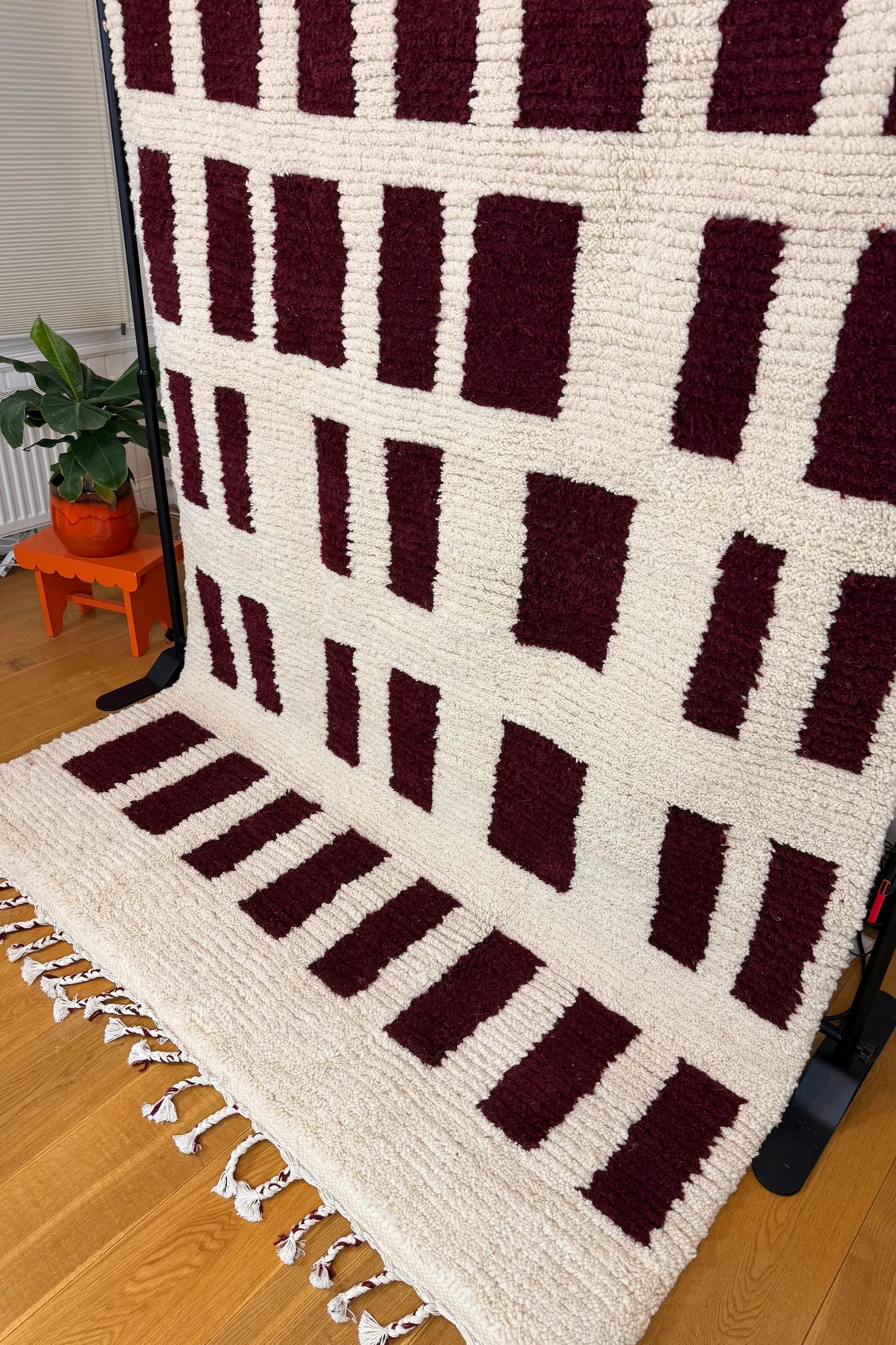 Narjess handmade Berber wool rug, side view showing the full burgundy rectangle grid pattern across the natural ivory wool surface, Tunisia.