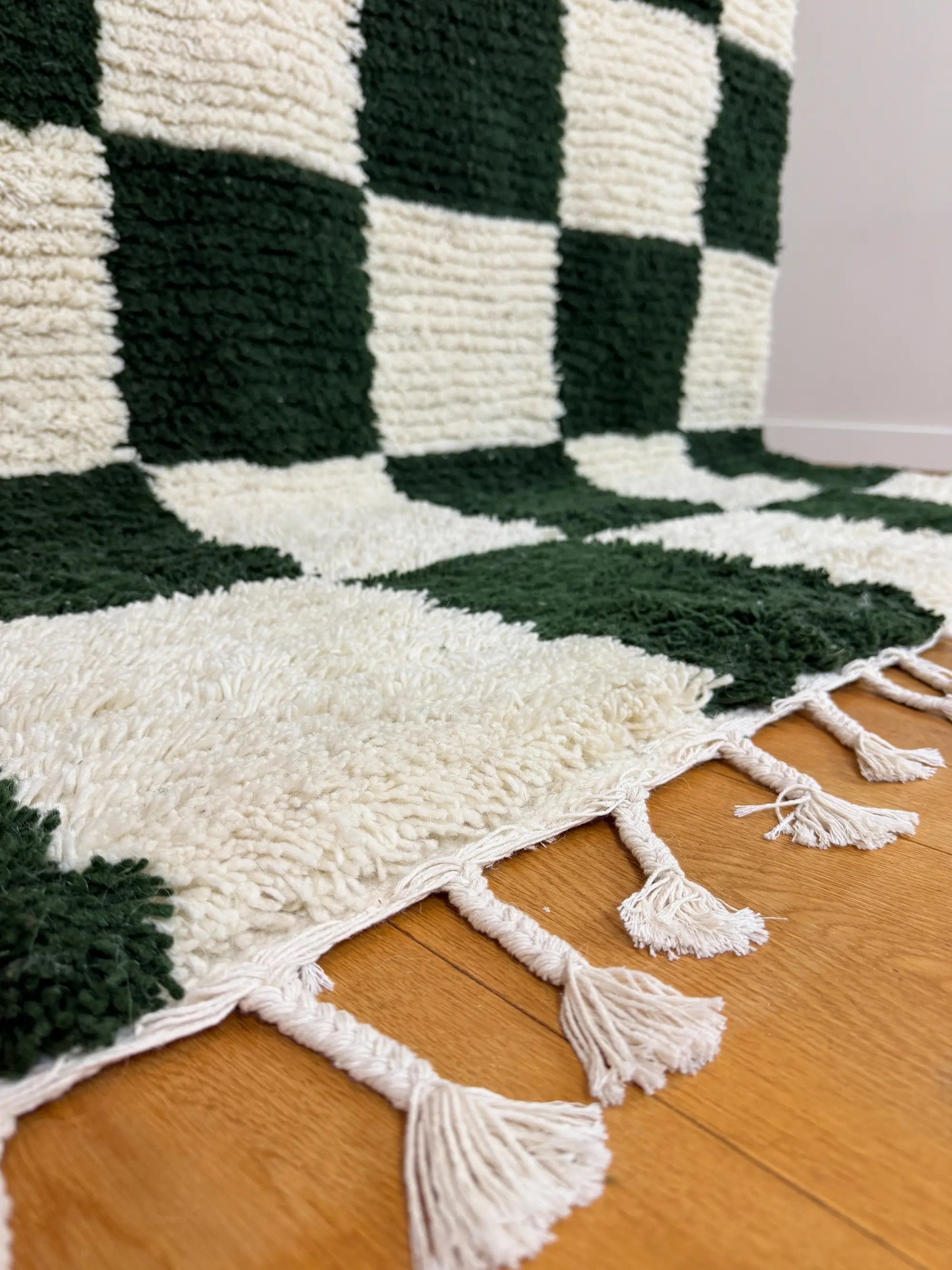 Close-up of the hand-knotted wool fringe on the Zeineb Berber rug, natural white tassels on oak floor, handmade in Tunisia.