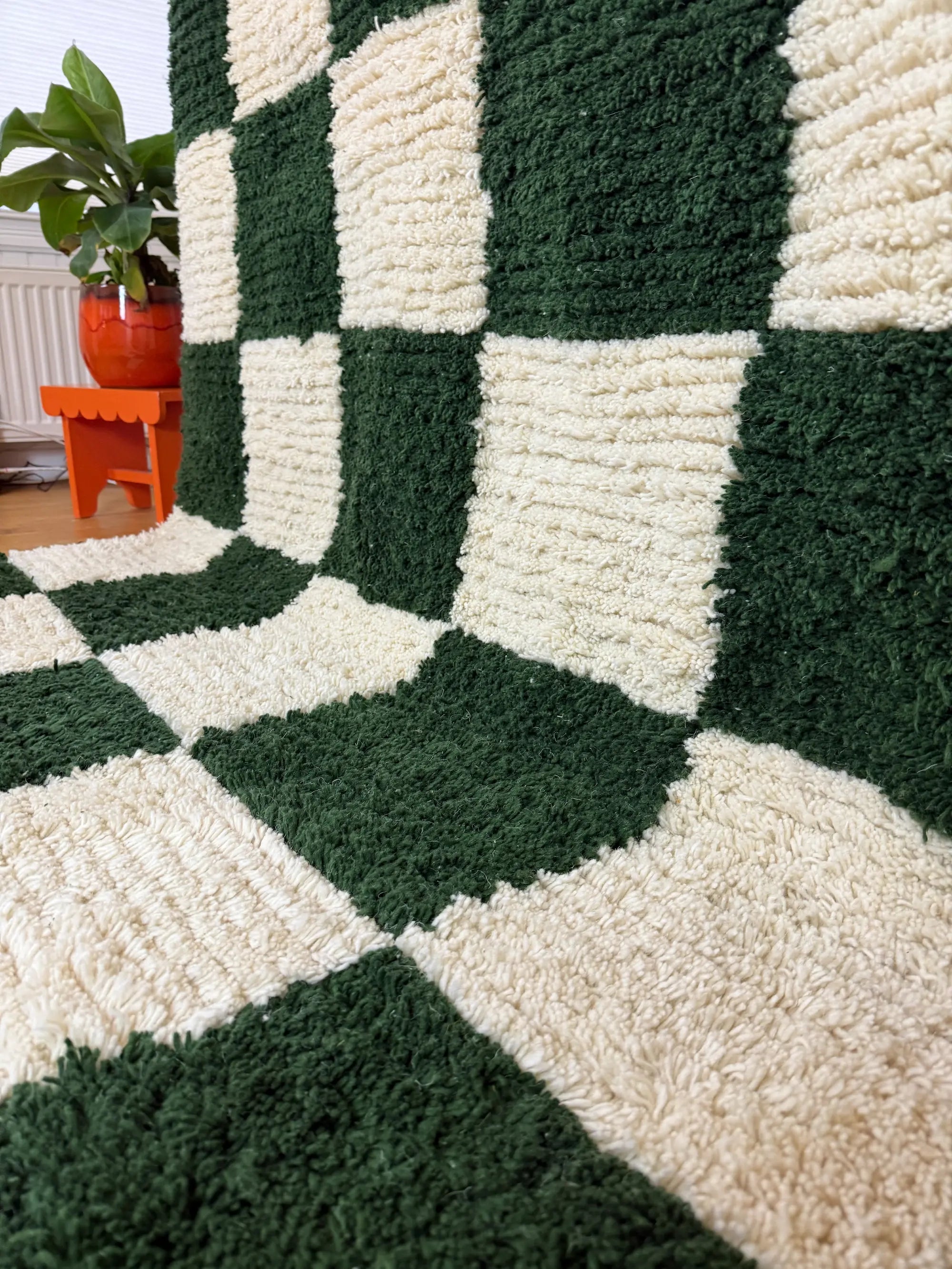 Close-up of hand-knotted checkered wool texture on the Zeineb Berber rug, showing the contrast between deep green and natural white squares.