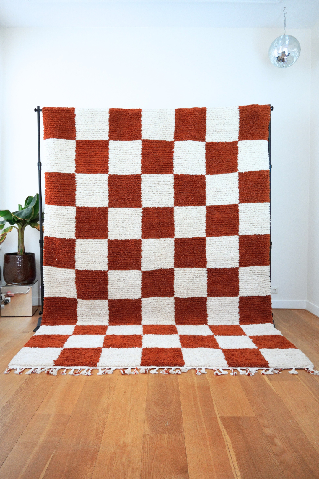Full front view of the Fatma handmade Berber rug with orange and cream checkered pattern, upright on wooden floor