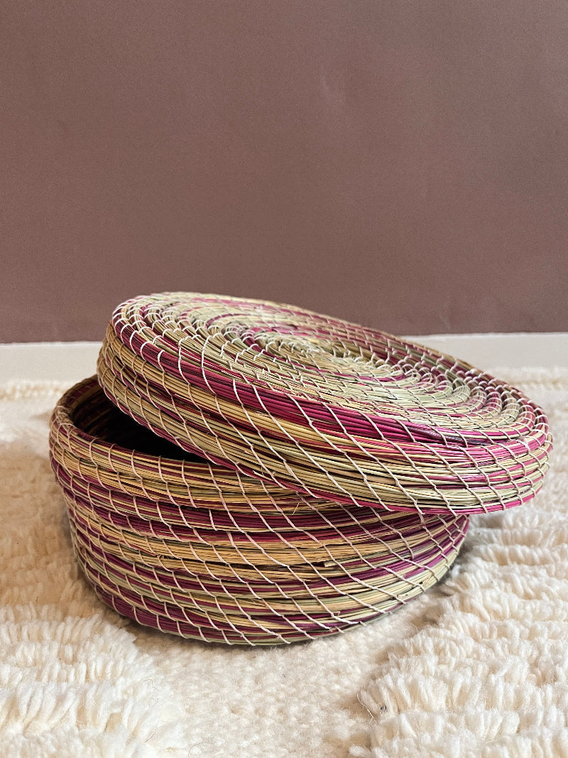 Angled view of Karima handmade basket in natural green & pink straw with top slightly open.