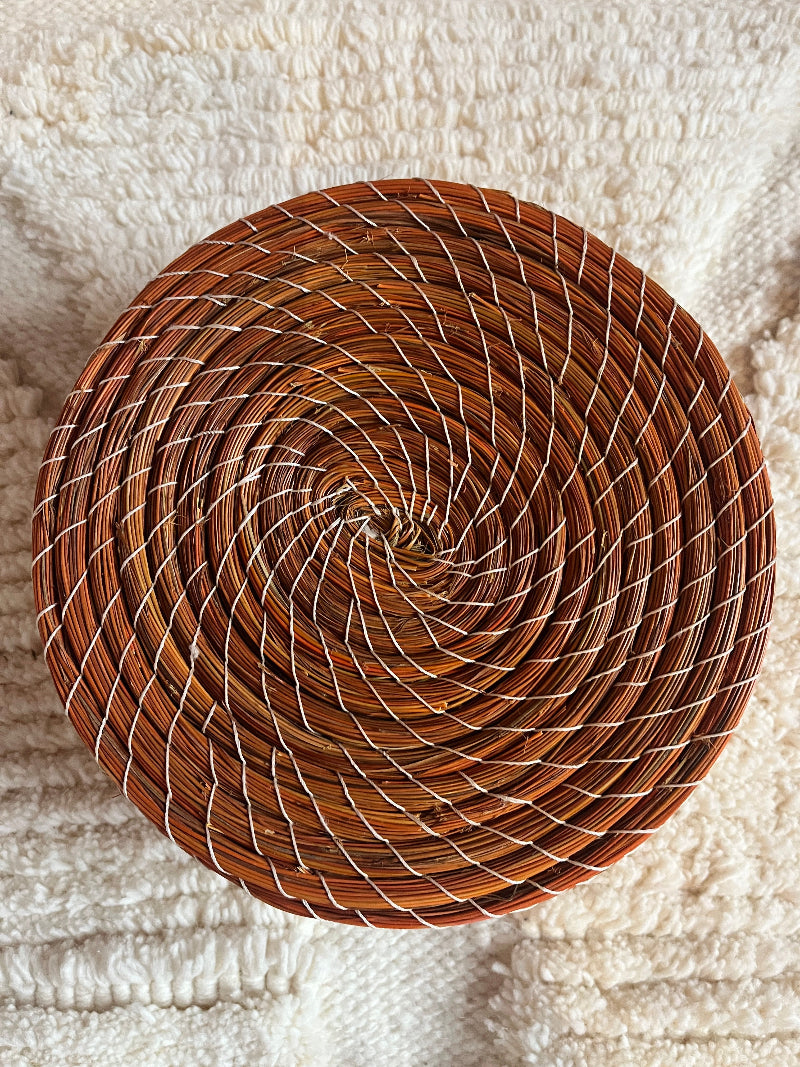 Overhead view of Karima handmade straw basket in orange.