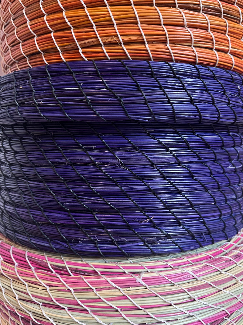 Three Karima straw baskets stacked, showing natural green and pink weave.