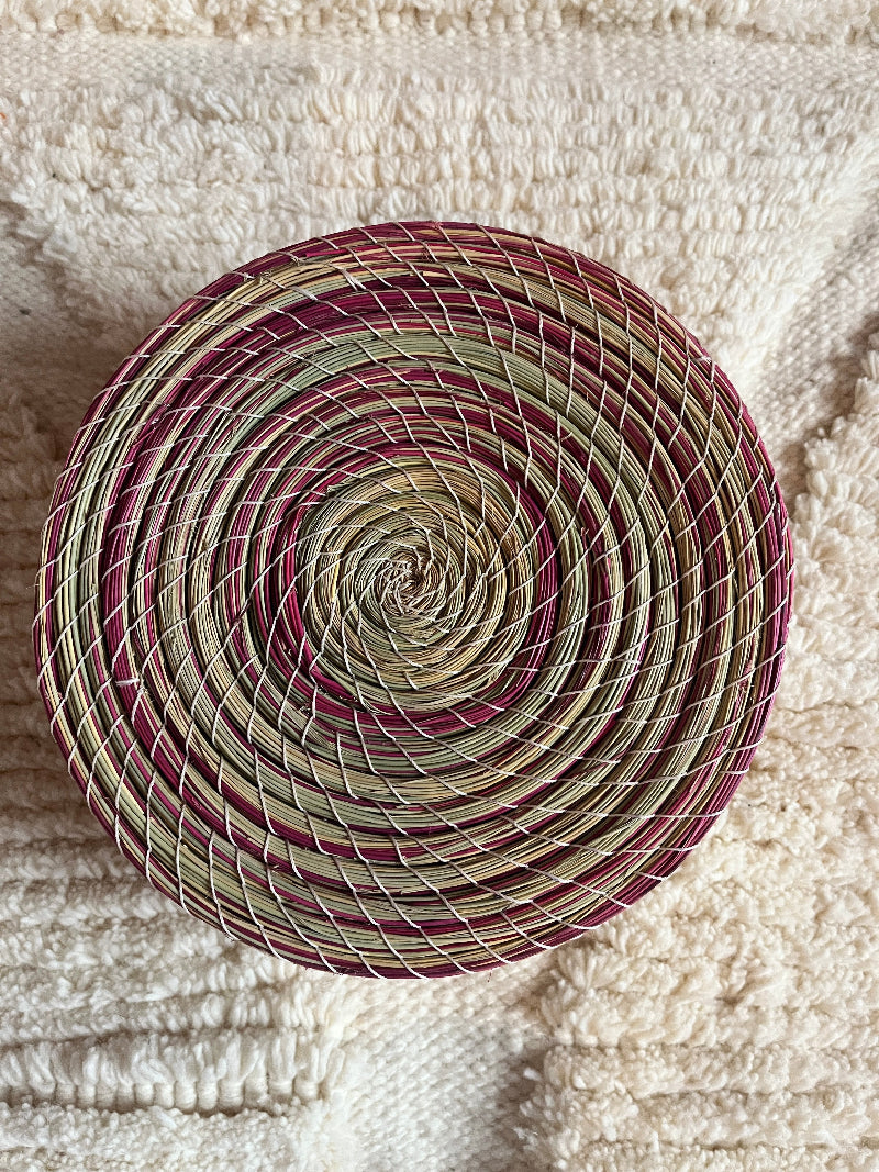 Overhead top view of Karima handmade straw basket with natural green and pink pattern.