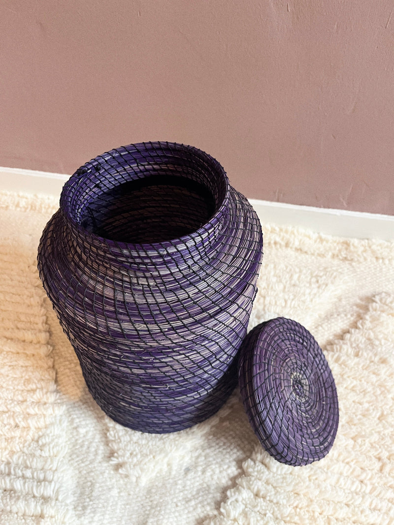 Angled view of handmade purple straw basket Nabila with lid.
