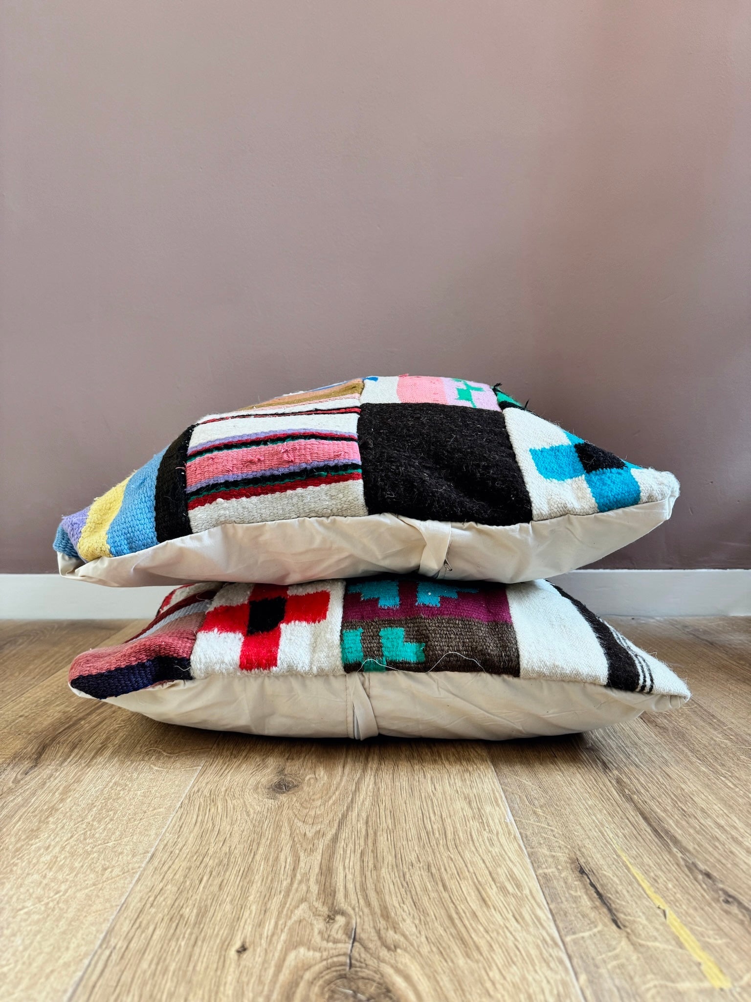 Two Rania patchwork wool cushion covers stacked, showing multicolor patterns.