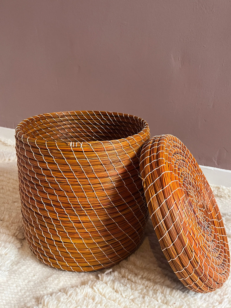 Angled view of orange handmade straw basket.