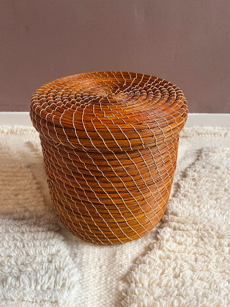 Woven brown basket on a textured white surface with a neutral background