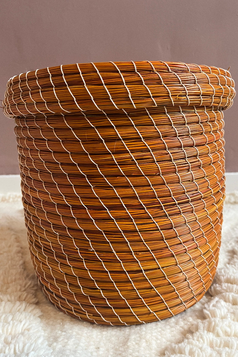 Handmade straw basket in orange weave, full view.