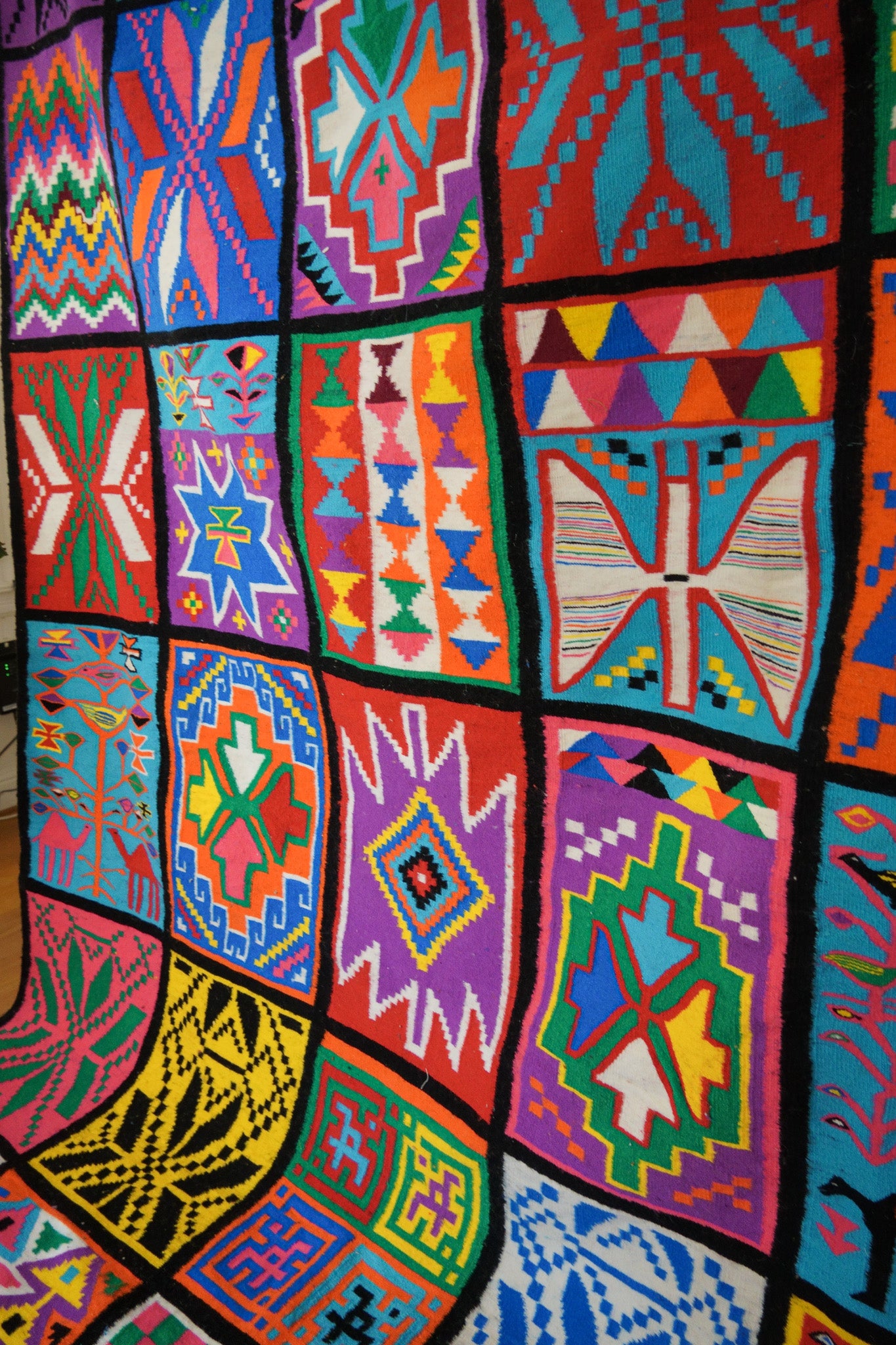 Close-up of multicolor geometric patchwork motifs on wool rug.