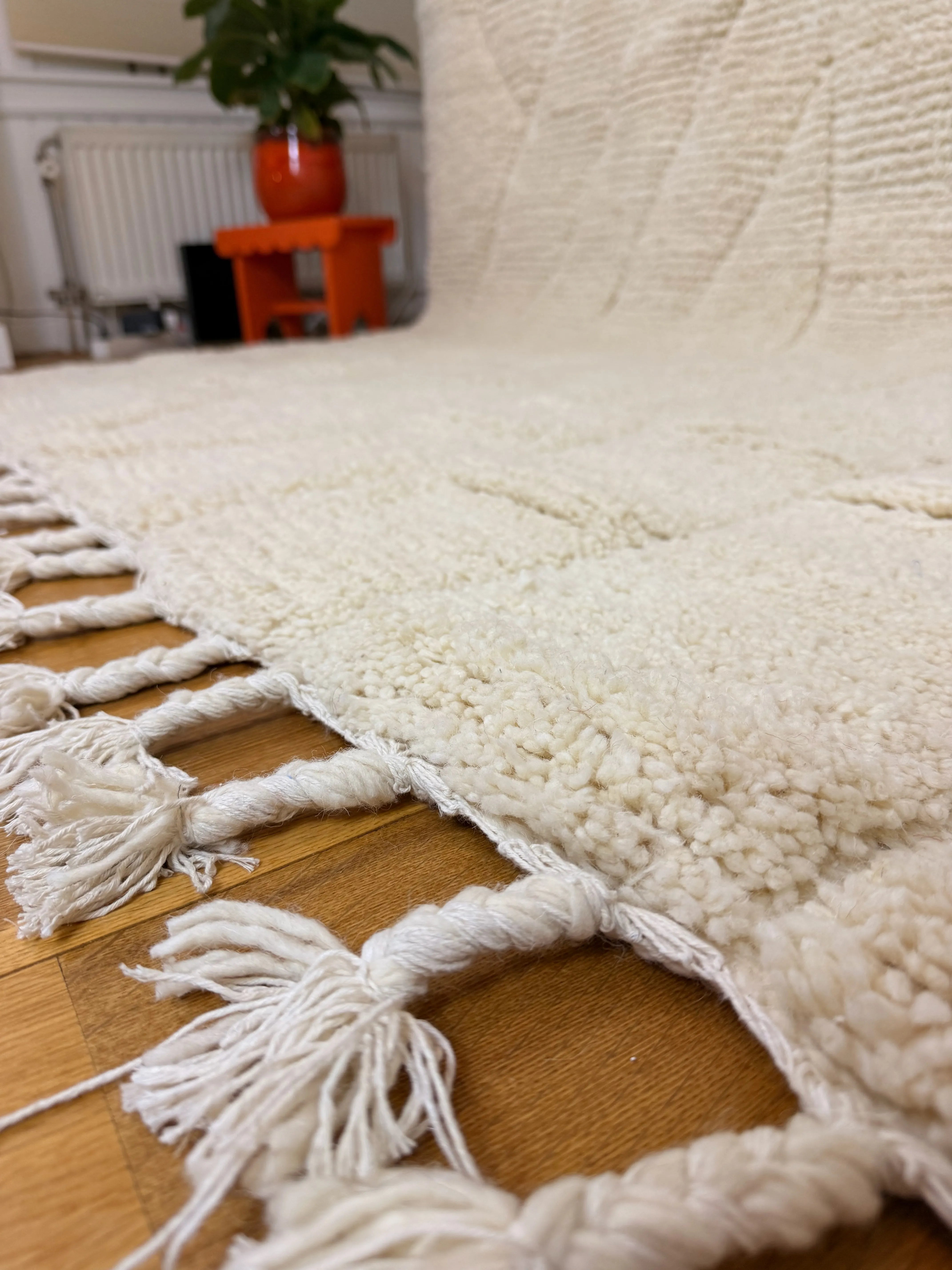 Close-up of the hand-knotted ivory fringe and raised line pattern on the Beya handmade Berber wool rug, Tunisia.