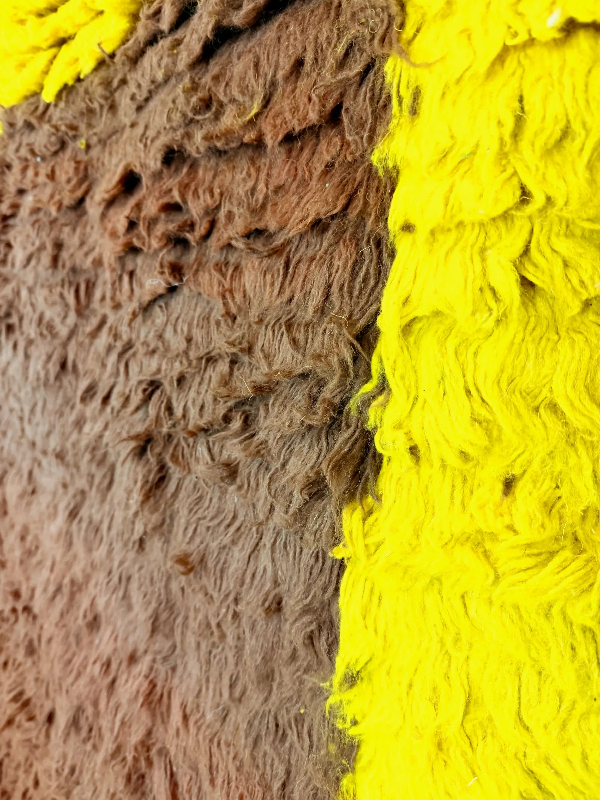 Close-up of the Faiza handmade Berber rug showing the contrast between the chocolate brown wool centre and the vivid yellow border, Tunisia.