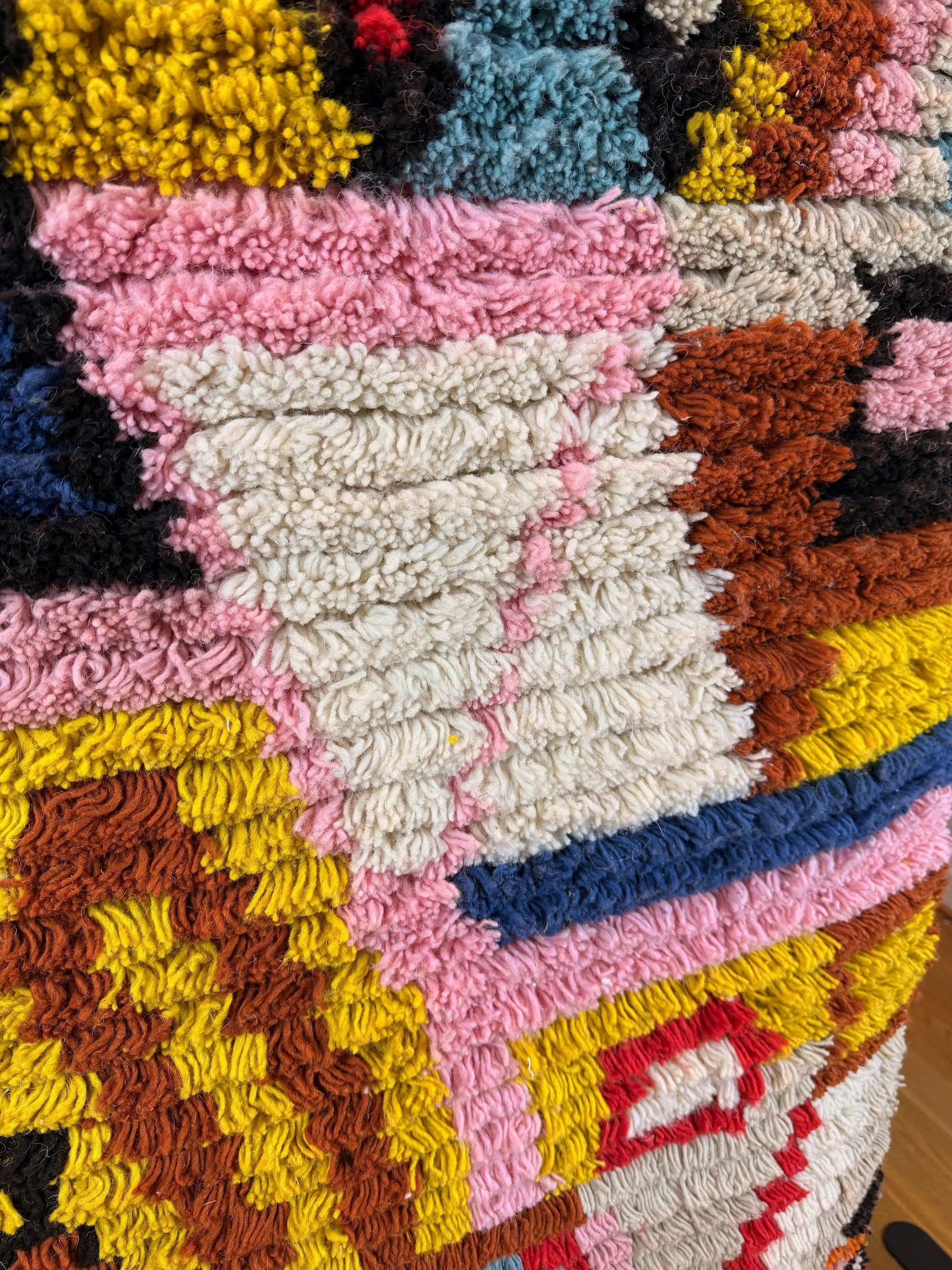 Close-up of the dense shaggy wool pile on the Hafsa Berber runner, showing the vivid multicolour abstract blocks in pink, yellow, cream and terracotta, Tunisia.