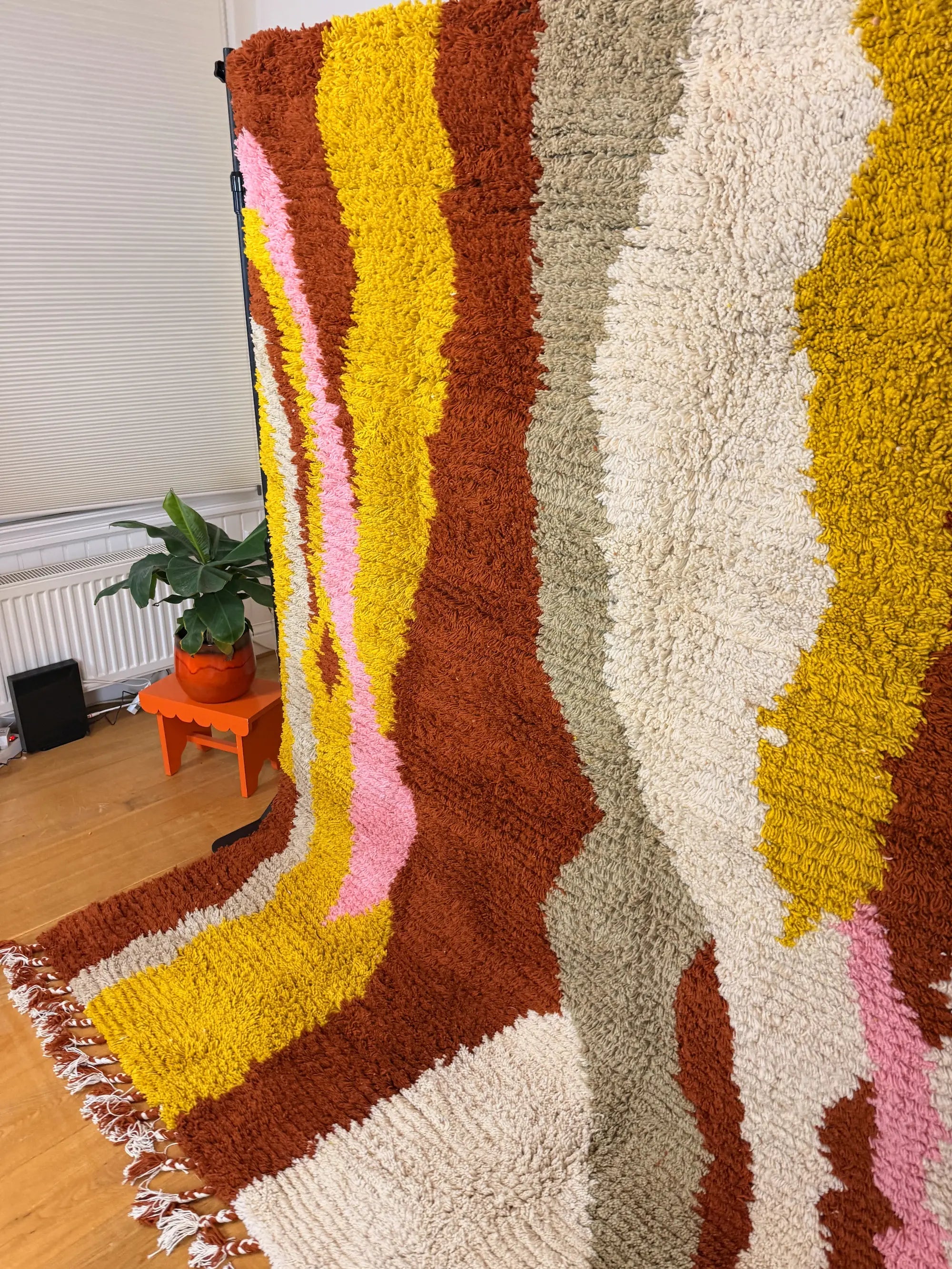Jamila handmade Berber wool rug, side view showing the full abstract colour band design in burnt orange, mustard yellow, pink, grey and cream wool, Tunisia.