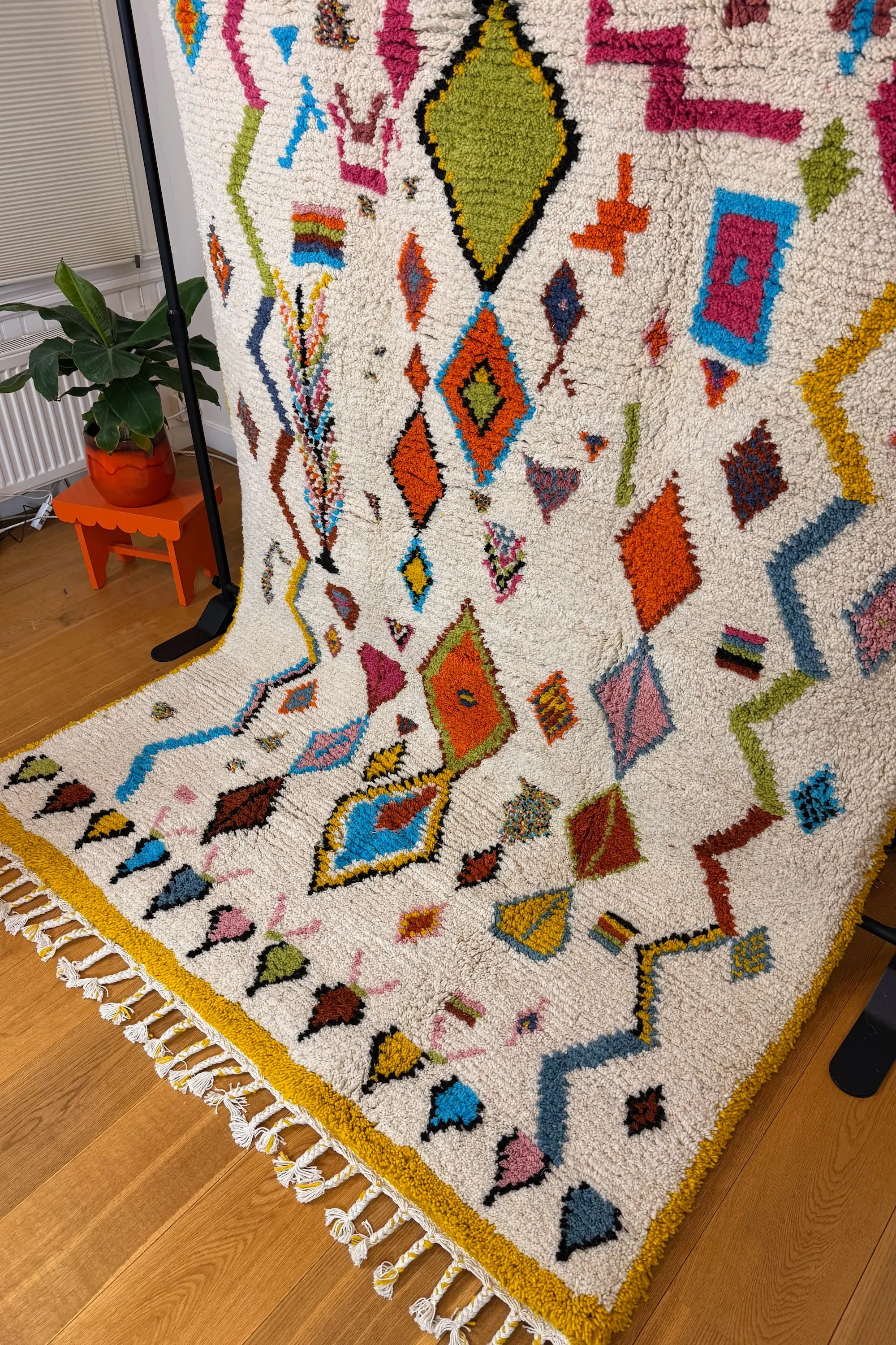Khadija handmade Berber wool rug, side view showing the full composition of multicolour Amazigh motifs on natural white wool with mustard yellow border, Tunisia.