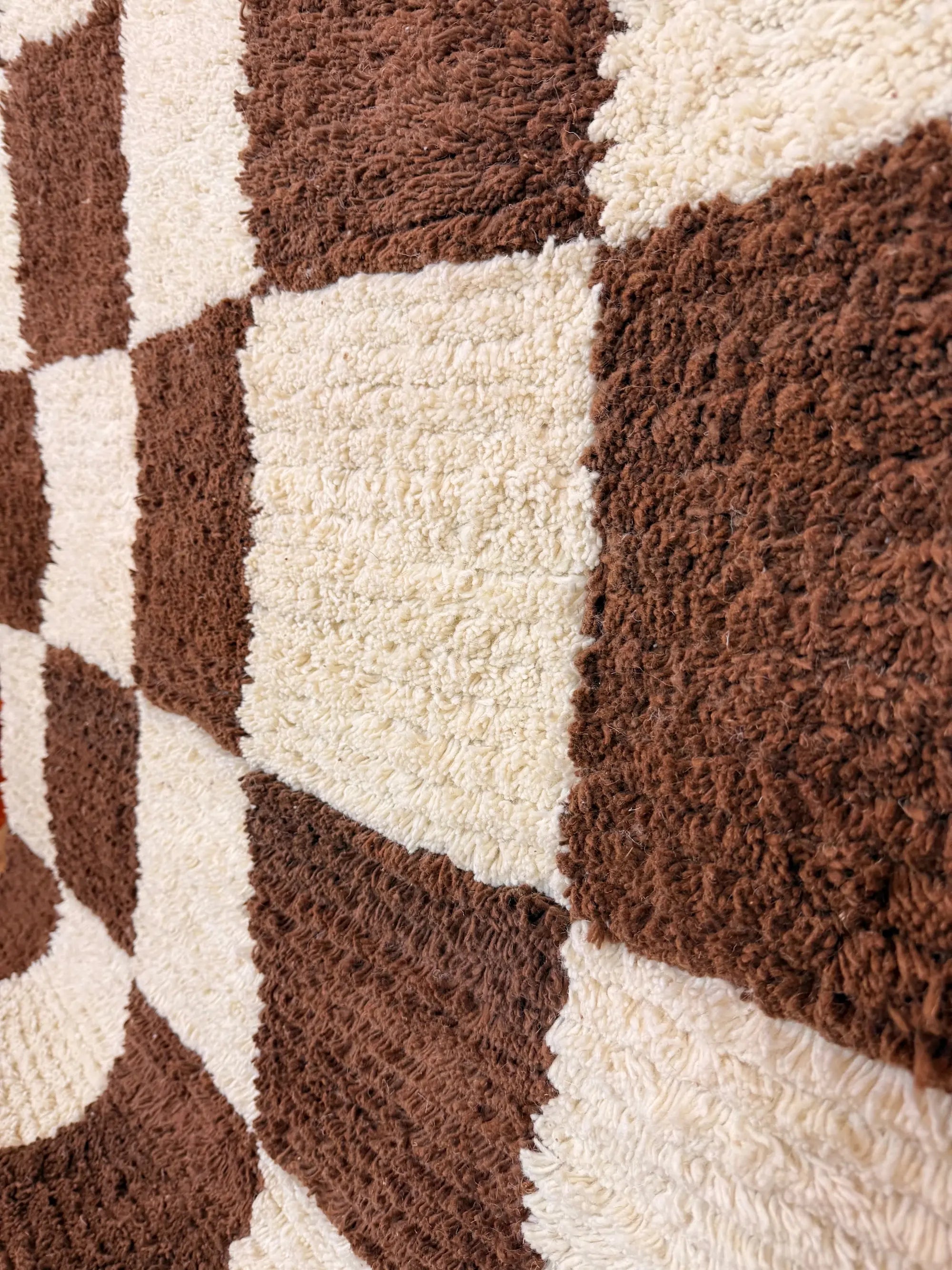 Close-up of Meriem Berber wool rug laid flat, showing the contrast between chocolate brown and natural white wool squares, Tunisia.