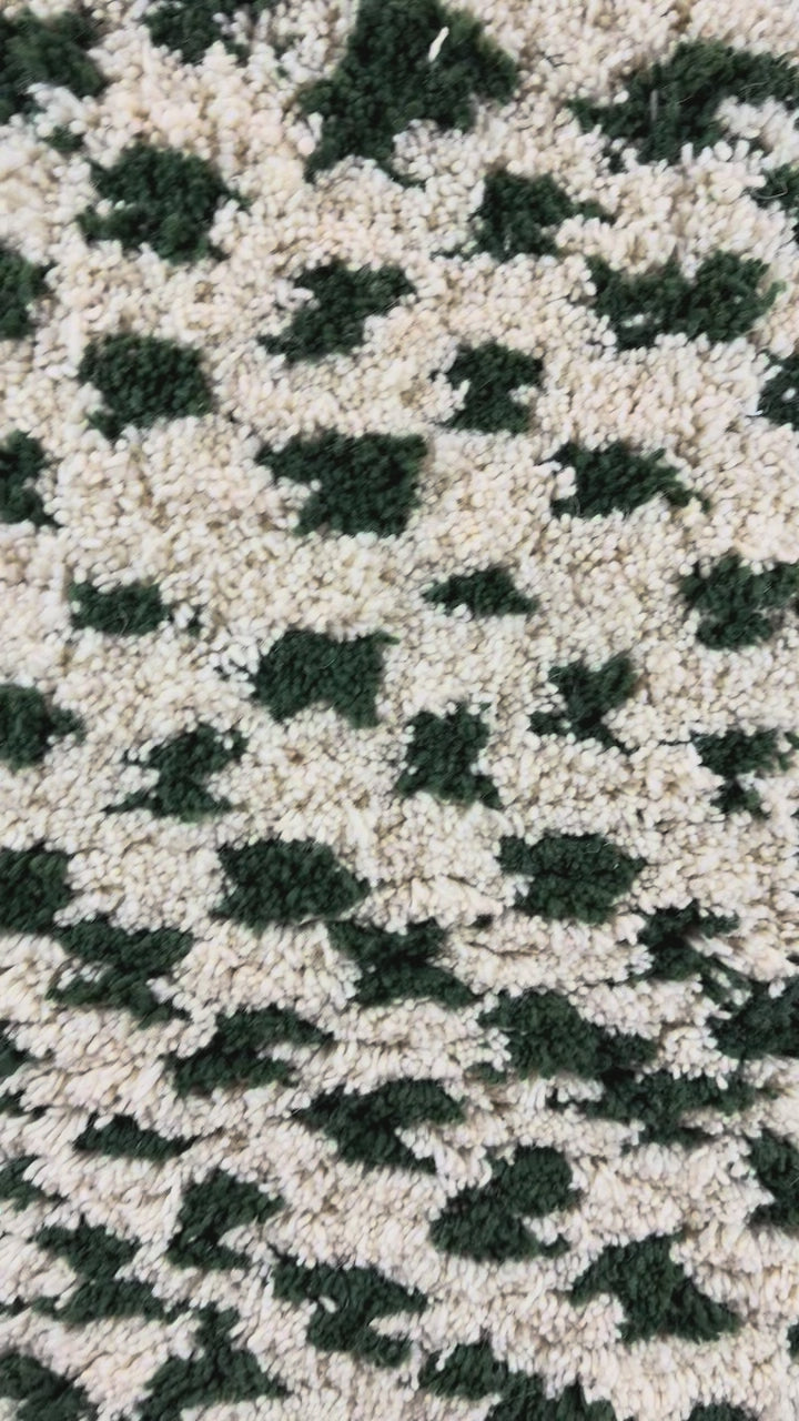 Mouna handmade shaggy Berber wool rug from Tunisia, showing the organic green spot pattern and high wool pile in motion, 90 × 160 cm.