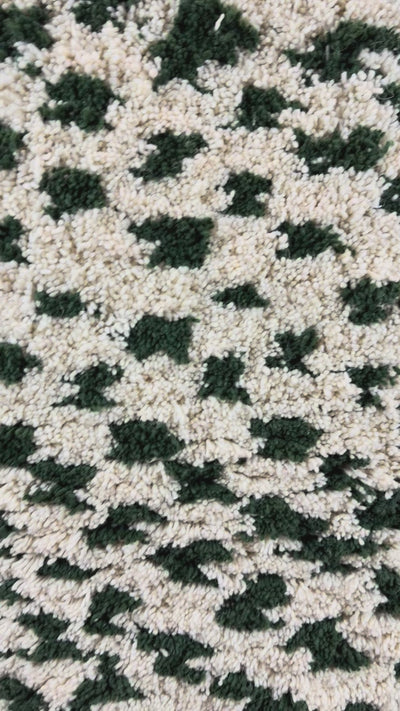 Mouna handmade shaggy Berber wool rug from Tunisia, showing the organic green spot pattern and high wool pile in motion, 90 × 160 cm.